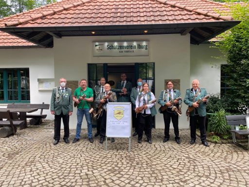 Gruppe von Musikern mit Instrumenten vor einem Gebäude im Freien, umgeben von Bäumen.