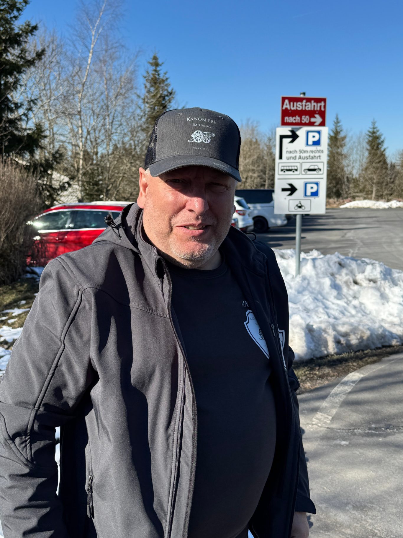 Andreas Darnauer Mann mit grauer Mütze und Jacke steht an einer Wintersportstation im Freien.
