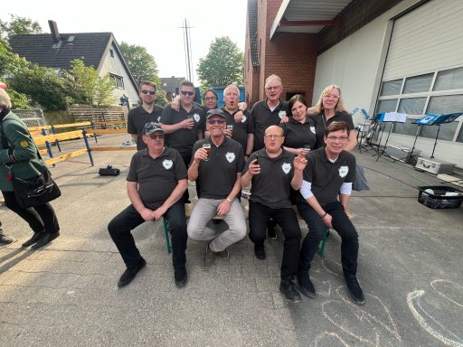 Gruppennfoto von zehn Personen in einheitlichen T-Shirts, lächelnd und posierend.