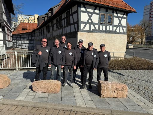 Gruppe von sieben Personen in schwarzer Kleidung vor einem historischen Gebäude.
