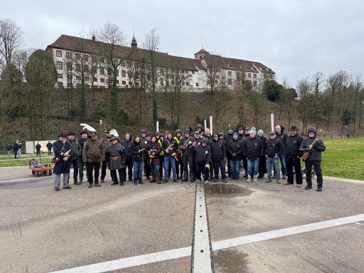 Gruppe von Menschen in einheitlicher Kleidung, posierend vor historischem Gebäude.